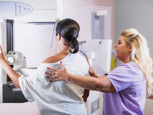 Medical staff assists woman during a breast cancer screening session with a mammogram machine