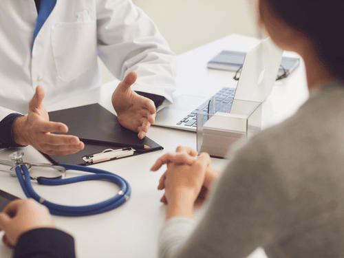 Doctor discusses medical concerns with patient at a desk during a healthcare consultation session