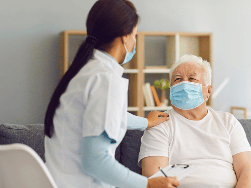 Nurse comforts and checks in on an elderly man during a home healthcare visit