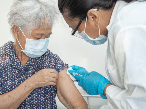 A nurse carefully administers a vaccine to an elderly woman during a health checkup