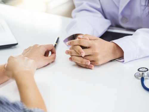 Doctor and patient sit across a desk, discussing a recent health check up in detail