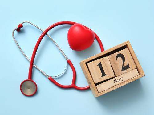 Stethoscope, red heart, and wooden May 12 calendar block symbolize health awareness and check-ups