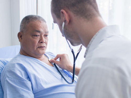 Doctor uses stethoscope to examine elderly patient’s chest during a hospital health assessment