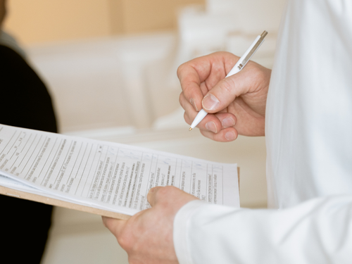 A healthcare professional reviews and writes on a patient form during a routine health check