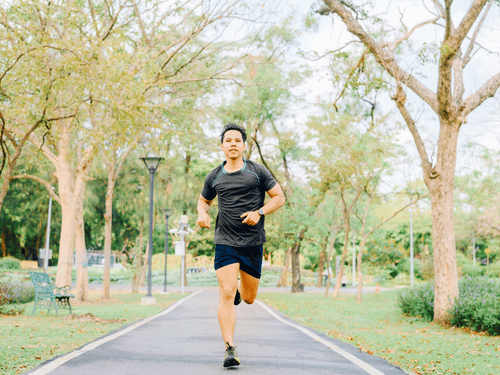 A man jogs through a tree-lined park path as part of his healthy lifestyle routine