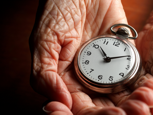 A health screening package reminder shown symbolically through elderly hands holding a classic pocket watch